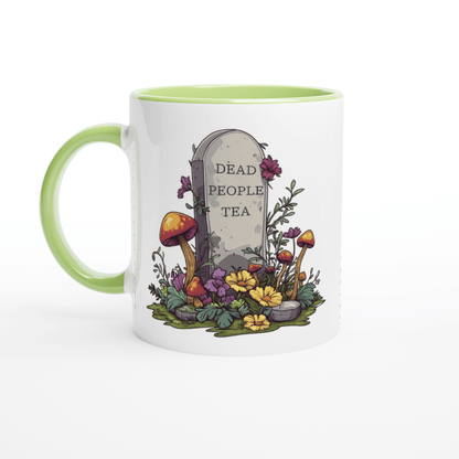 A white ceramic mug with a green handle features an illustration of a tombstone surrounded by mushrooms and flowers that reads "Dead People Tea.