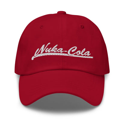 A red dad hat features "Nuka-Cola" embroidered in white script across the front panel.