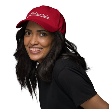 A person wearing a red Nuka Cola embroidered dad hat smiles while looking over their shoulder.