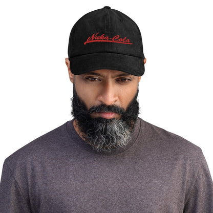 A man wearing a black Nuka Cola embroidered dad hat looks directly at the camera.
