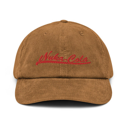 A brown corduroy dad hat features red embroidered "Nuka Cola" lettering across the front.