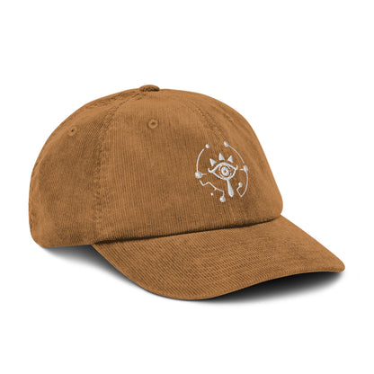 A brown Zelda Sheikah embroidered cap features a white eye symbol design on the front panel.