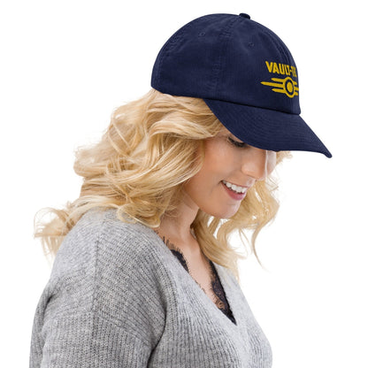 A person wearing a blue Vault-Tec baseball cap embroidered with the Fallout logo.