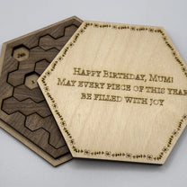 The image shows a Hexagon Calendar Puzzle Gift Edition featuring wooden tiles arranged in a hexagonal shape and inscribed with "Happy Birthday, Mum!