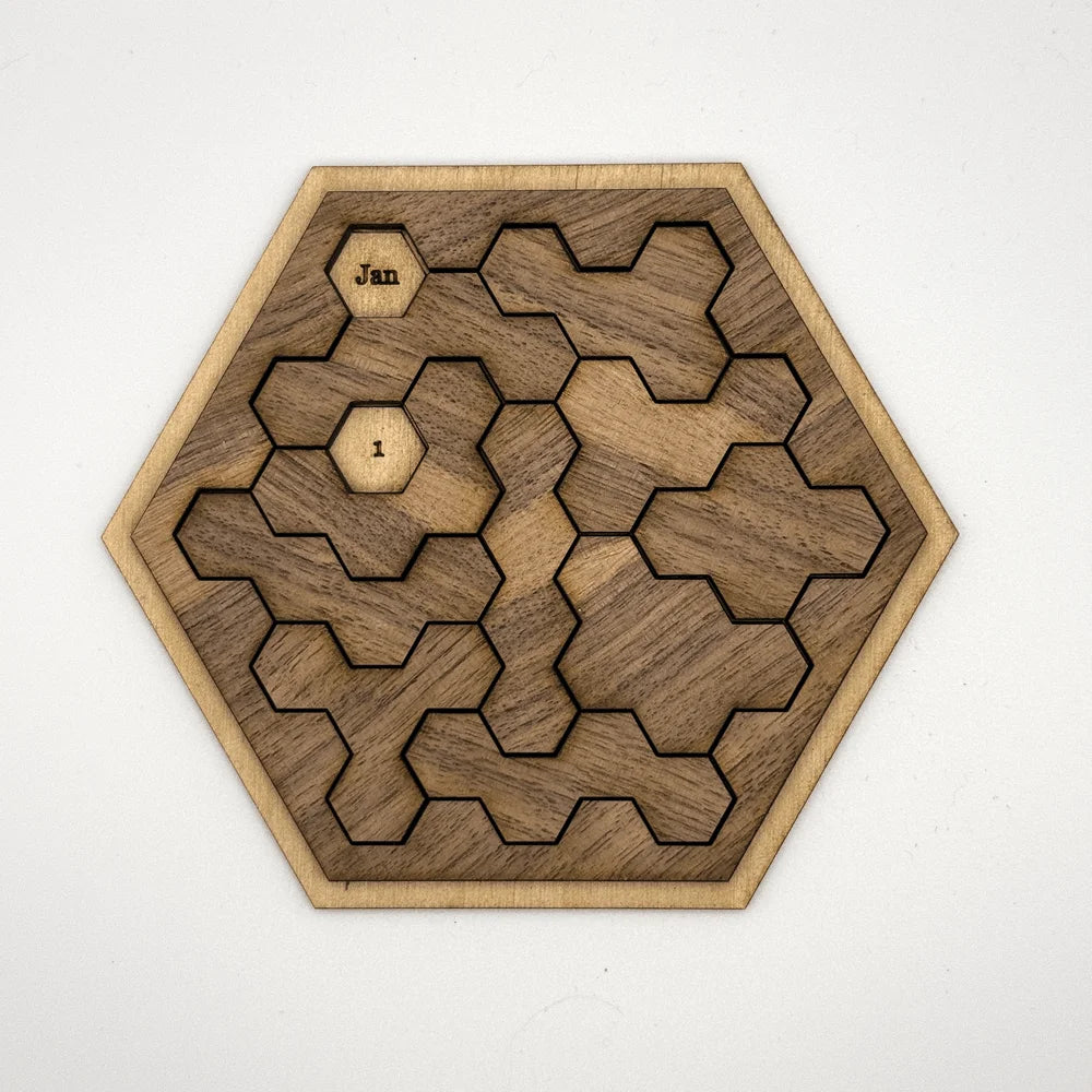 A wooden hexomino puzzle, inspired by Star Trek, features interlocking pieces and labels "Jan" and "I" on two of them.