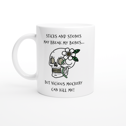 A white mug displays a cartoon skull adorned with a flower and text referencing "Sticks and Stones" and "Vicious Mockery," inspired by Dungeons & Dragons.