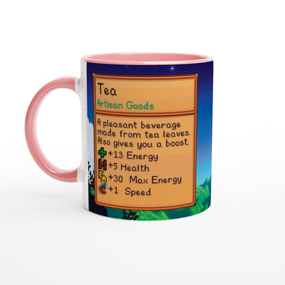 A pink-handled mug displays a Stardew Valley design featuring information about tea as an artisan good.