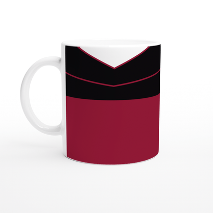A white mug displays a design inspired by a Star Trek TNG uniform featuring red, black, and white panels.