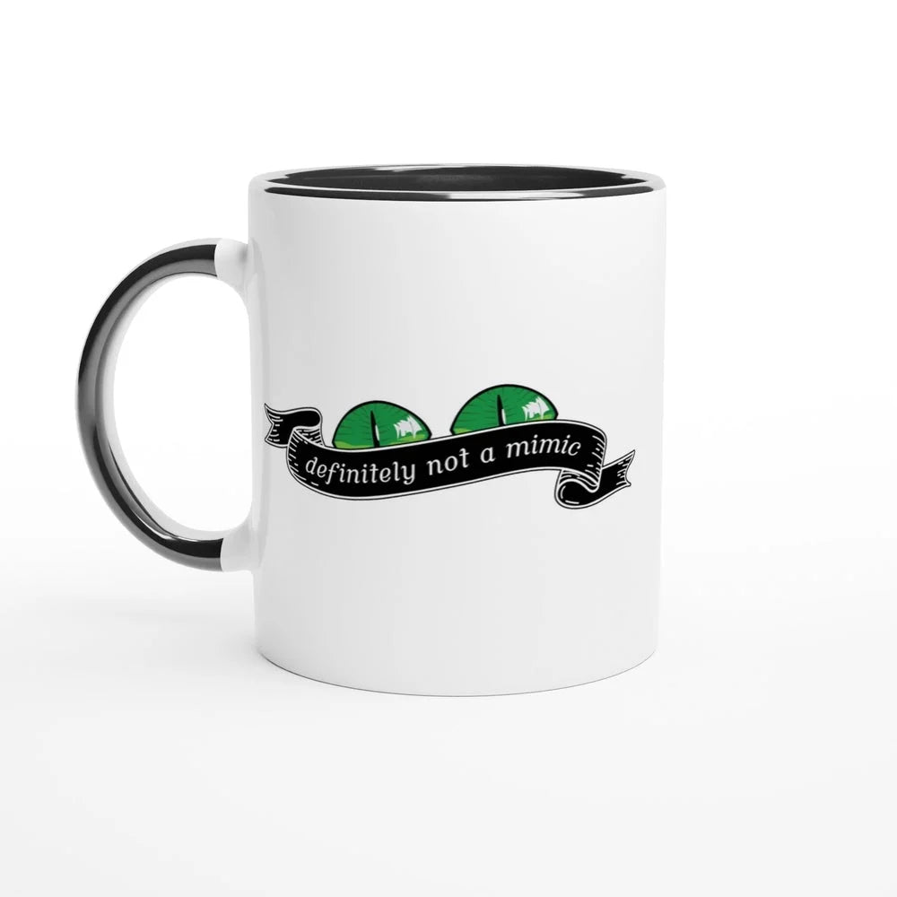 A white mug with a black handle and rim features a graphic of green eyes and a banner reading "definitely not a mimic," referencing the D&D tabletop RPG game.