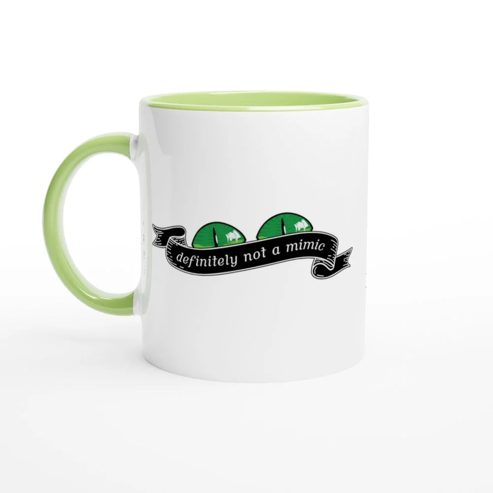A white mug with a green handle and rim features a cartoon illustration of a D&D mimic creature with the words "definitely not a mimic" displayed on a banner.