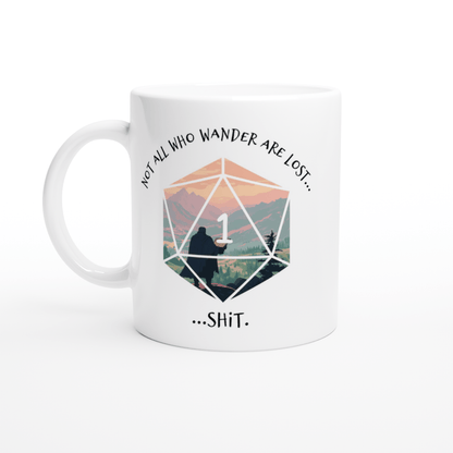 A white ceramic mug displays a D&D-style D20 die graphic with a mountain landscape inside and the words "Not all who wander are lost" curving above it, and "...shit" below.