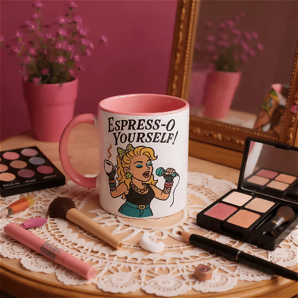 Retro mug with 'Espress-O Yourself!' pop diva Madonna style design on a table with 80s makeup items and a pink wall.