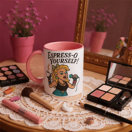Retro mug with 'Espress-O Yourself!' pop diva Madonna style design on a table with 80s makeup items and a pink wall.
