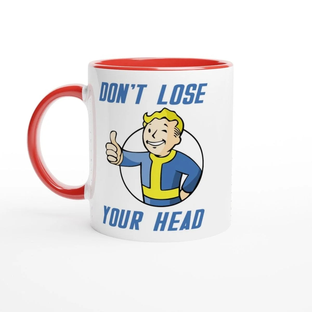 A white mug with a red handle and rim features Vault-Tec branding and cartoon character giving a thumbs up alongside the words "Don't Lose Your Head," referencing the Fallout video game.