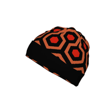 A knitted winter hat featuring a red and orange hexagonal pattern inspired by The Shining Overlook Hotel carpet.