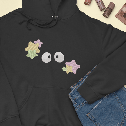 A black Soot Sprites embroidered hoodie, inspired by Studio Ghibli, features four star-shaped sprites with large eyes across the chest.