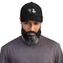 A person wearing a black Jujutsu Kaisen embroidered baseball cap featuring a betta fish design resembling a yin yang symbol.