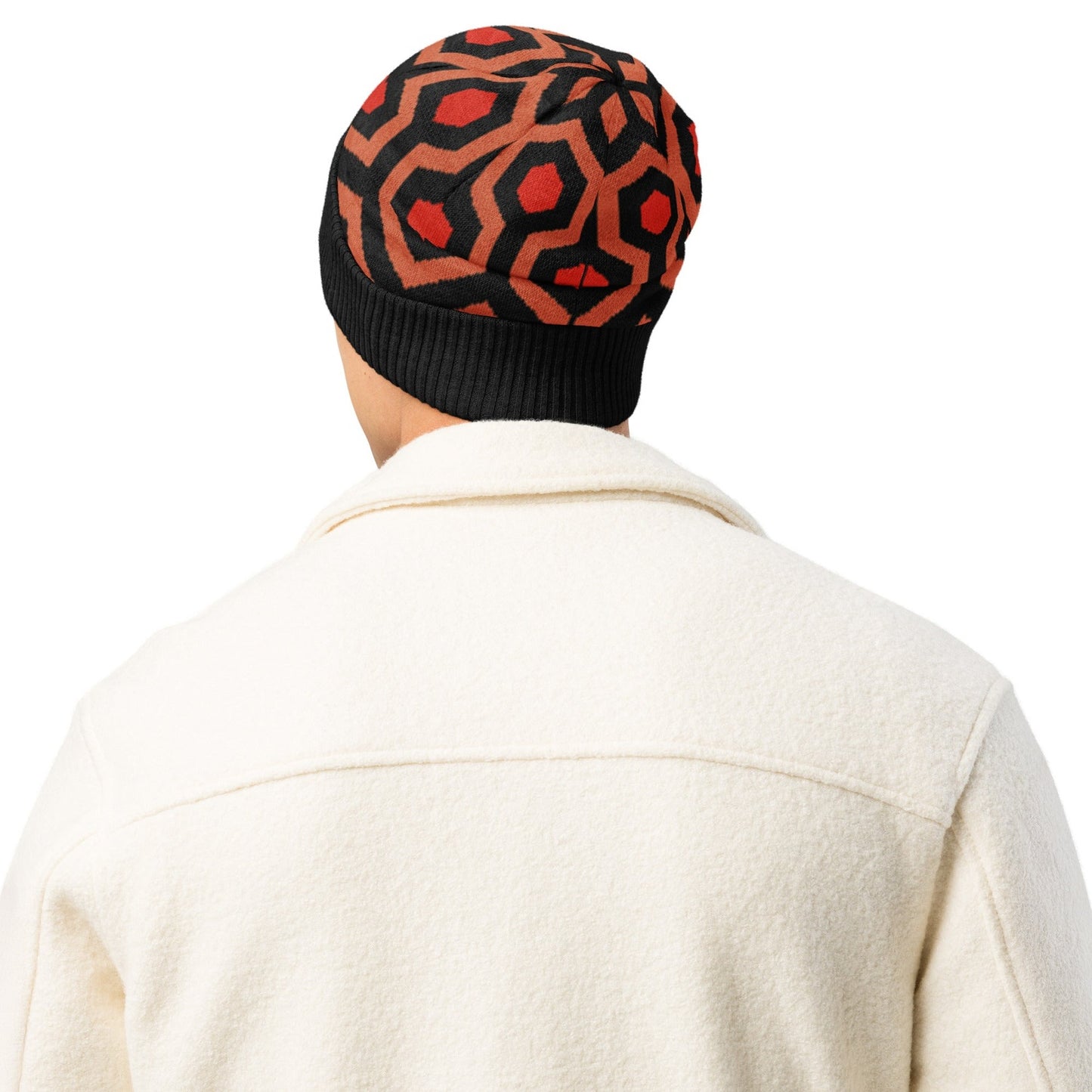 Man wearing an Overlook Hotel carpet pattern knitted beanie in orange, black and red on a white background