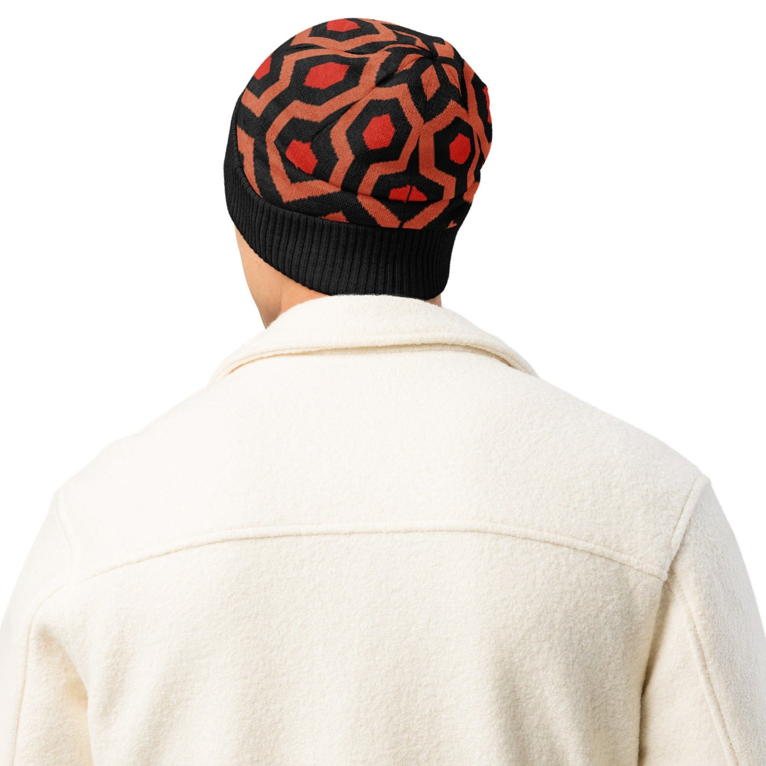 Man wearing an Overlook Hotel carpet pattern knitted beanie in orange, black and red on a white background