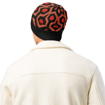 Man wearing an Overlook Hotel carpet pattern knitted beanie in orange, black and red on a white background