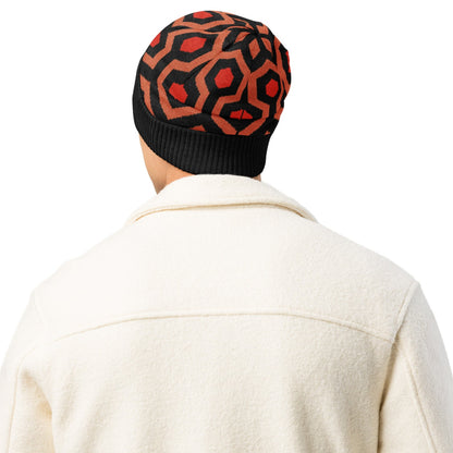 Man wearing an Overlook Hotel carpet pattern knitted beanie in orange, black and red on a white background