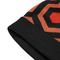 A close-up view of the black ribbed cuff on a knitted beanie featuring the orange and brown Overlook Hotel carpet pattern inspired by The Shining.