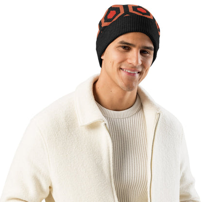 Man wearing an Overlook Hotel carpet pattern knitted beanie in orange, black and red on a white background