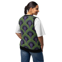A person wearing a v-neck knitted sweater vest featuring a green and purple Room 237 wallpaper pattern inspired by horror films.