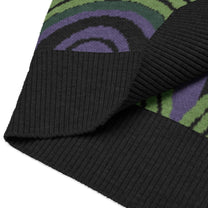 Close-up view of the Room 237 wallpaper pattern on a knitted sweater vest featuring green, purple, and black concentric swirls.