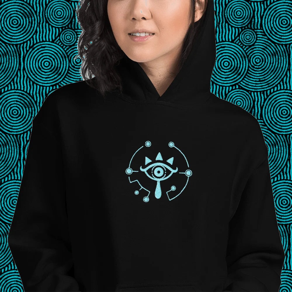 A person wears a black Zelda Sheikah Eye embroidery hoodie featuring a glow-in-the-dark design inspired by The Legend of Zelda: Tears of the Kingdom and Breath of the Wild.
