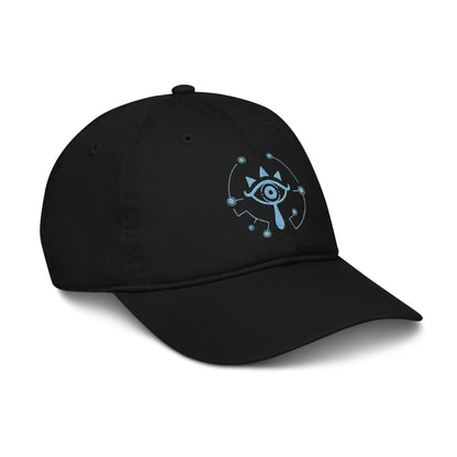 A black dad hat features an embroidered Sheikah eye symbol from Tears of the Kingdom that glows in the dark.