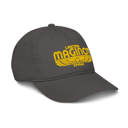 A gray baseball cap features an embroidered logo of "USCSS Maginot" with wings and a number below it.