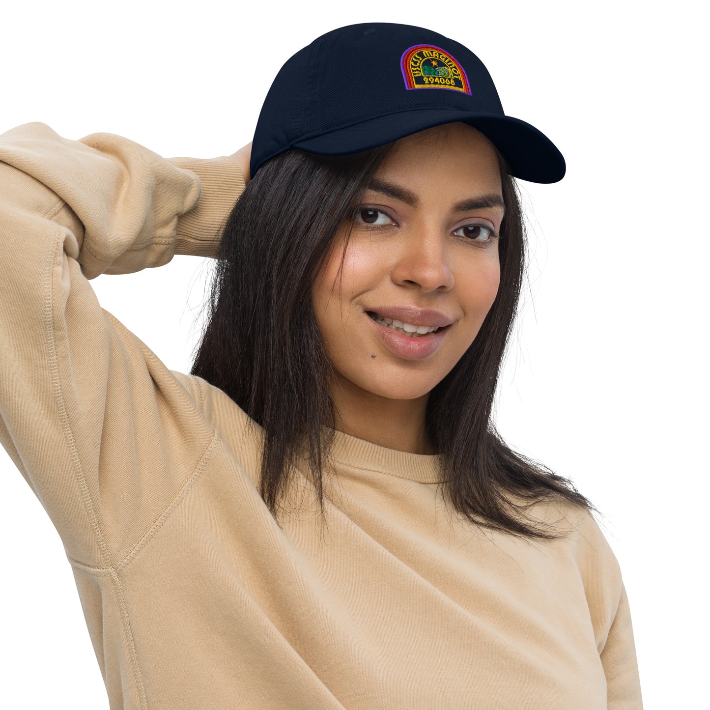 A person wearing a navy blue baseball cap featuring an embroidered logo that reads "USCS Maginot" in rainbow colors.