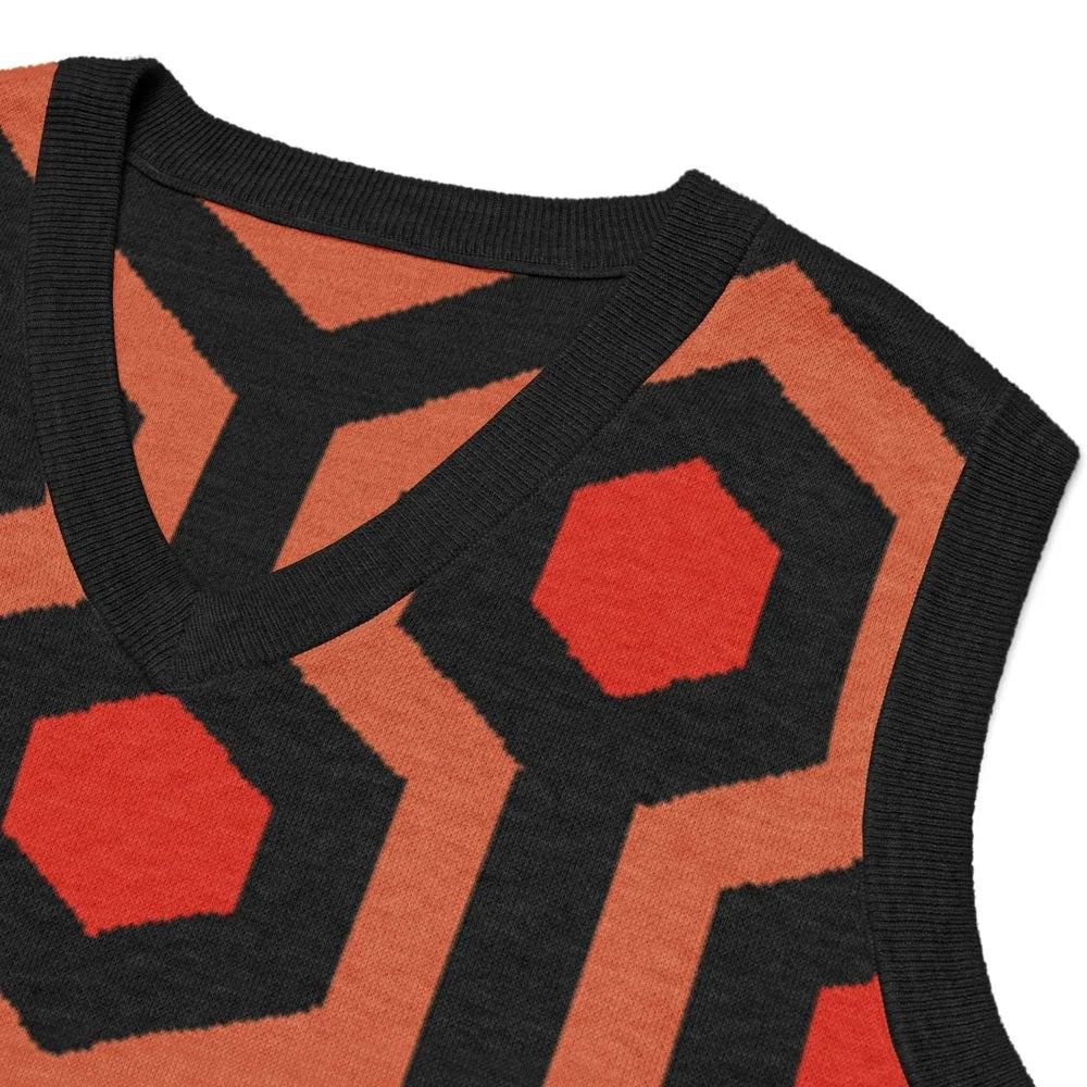Close-up of a V-neck knitted sweater vest featuring an orange and black Overlook Hotel carpet pattern.