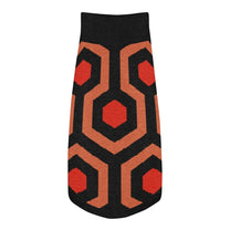 A knit pet sweater featuring a black, orange, and red geometric pattern inspired by the Overlook Hotel carpet.