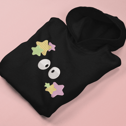 A black Soot Sprites embroidered hoodie, inspired by Studio Ghibli, displays stylized star and sprite designs on the front pocket.