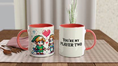 A white mug with a red handle and rim features pixel art of Link and Zelda from The Legend of Zelda, along with the words "You're My Player Two.