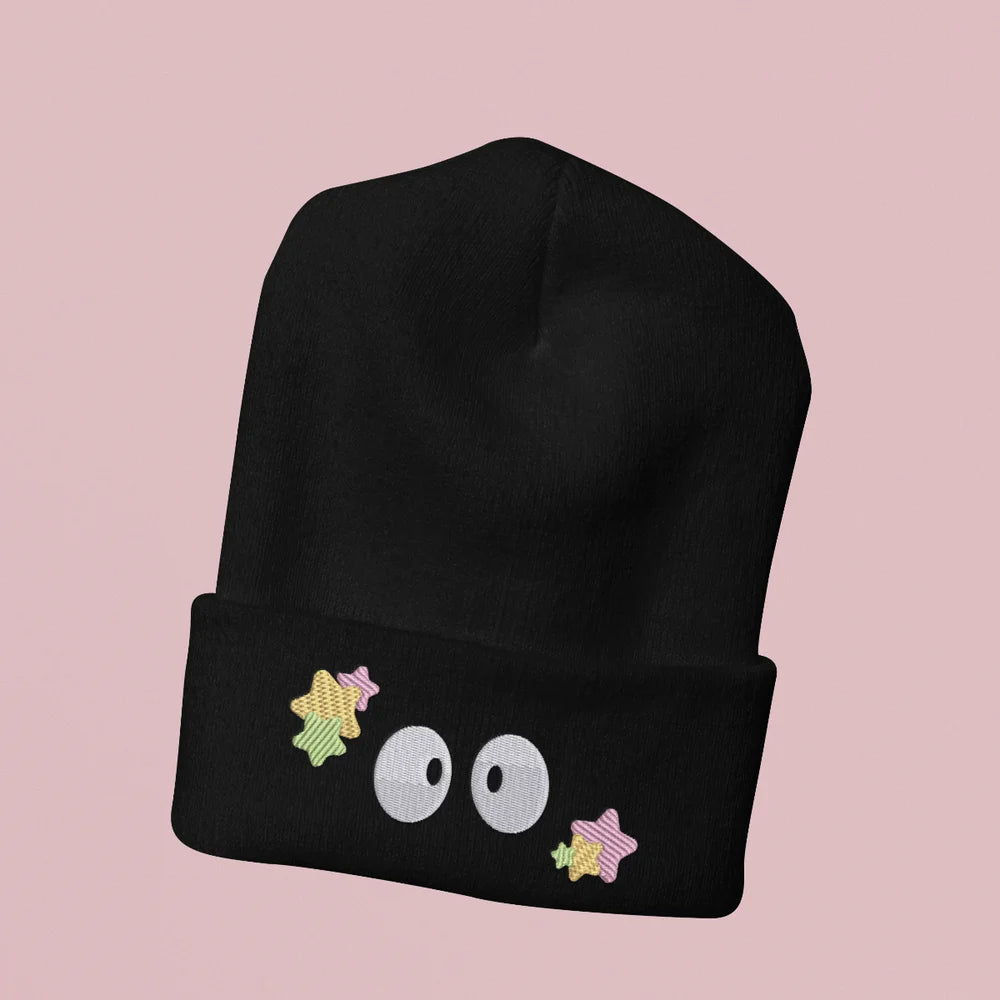 A black Soot Sprites beanie features embroidered stars and three large eyes inspired by Ghibli's Susuwatari.