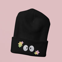 A black Soot Sprites beanie features embroidered stars and three large eyes inspired by Ghibli's Susuwatari.