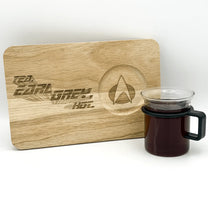 A wooden chopping board displays "Tea, Earl Grey, Hot" lettering and the Starfleet delta logo, next to a mug of dark tea.
