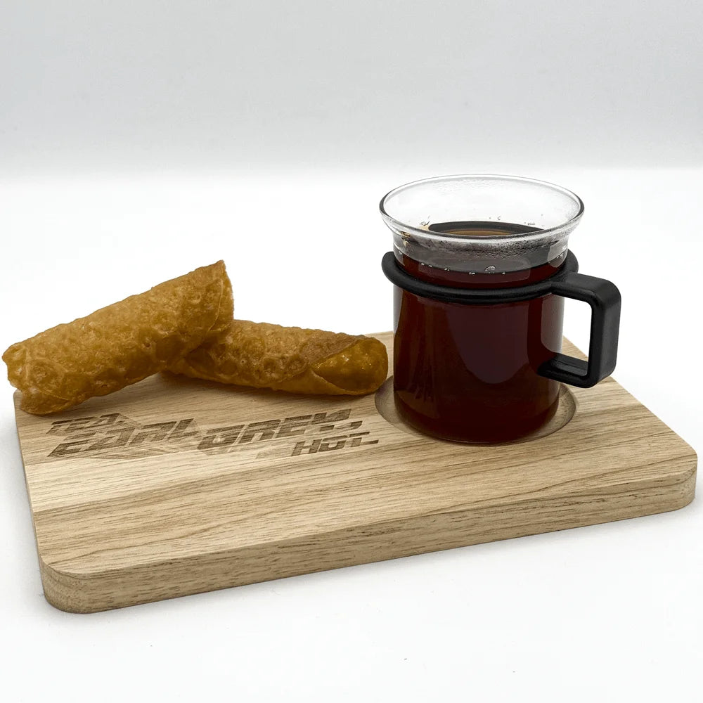 A wooden chopping board displays a glass of "Tea, Earl Grey, Hot" and a pile of golden-brown pastries.