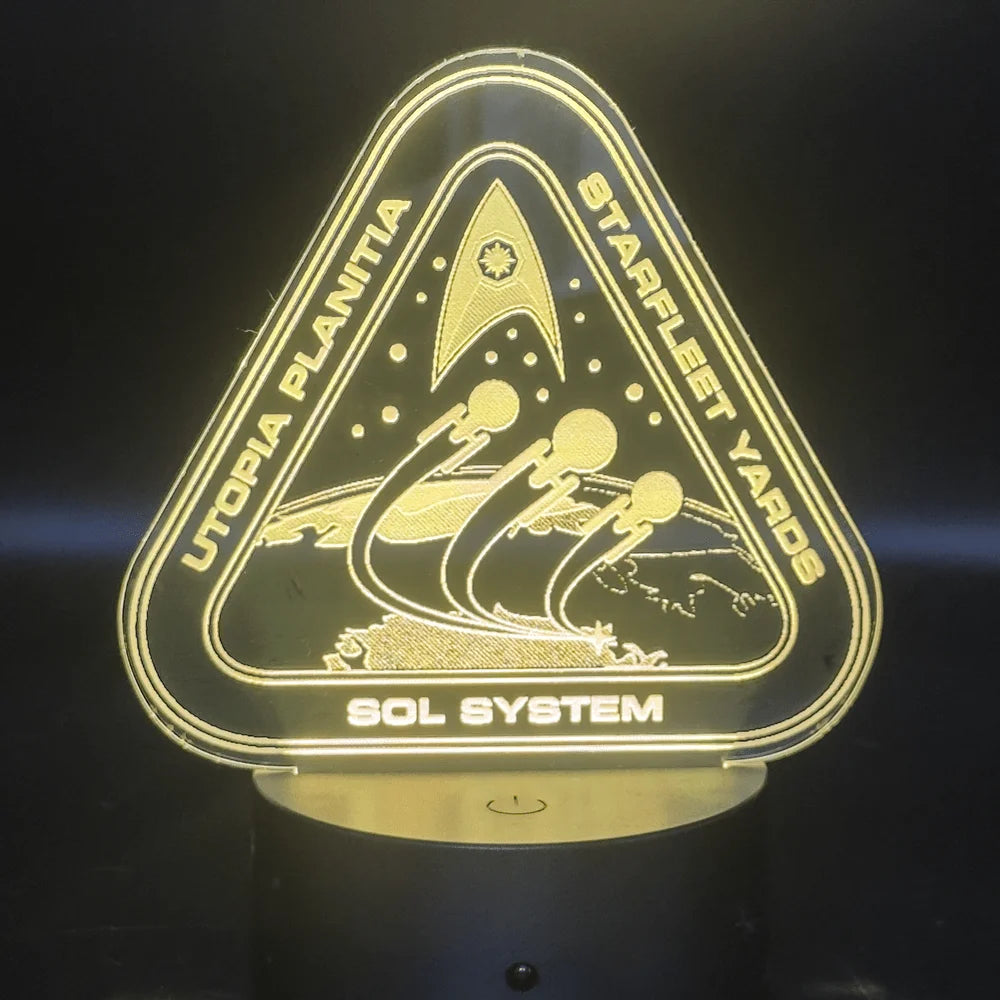 The illuminated acrylic lamp features an engraved design depicting a Starfleet Yards logo with "Utopia Planitia" and "Sol System" text, referencing the Star Trek universe.