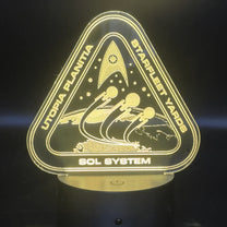 The illuminated acrylic lamp features an engraved design depicting a Starfleet Yards logo with "Utopia Planitia" and "Sol System" text, referencing the Star Trek universe.