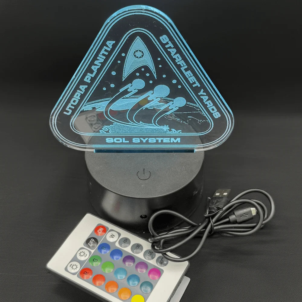 An LED engraved acrylic lamp depicts a triangular sign labeled "Utopia Planitia Starfleet Yard" and "Sol System," referencing the Star Trek universe.