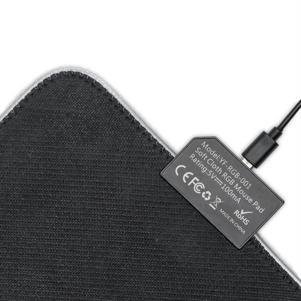 A black-edged desk mat features a soft cloth surface and an attached USB cable for its RGB lighting, as indicated by the model number "YF-RGB-001".