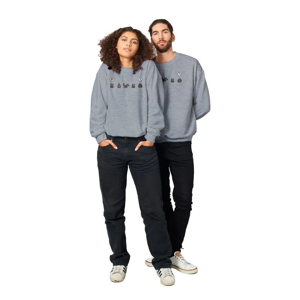 A man and a woman stand posing while wearing grey Stardew Valley crewneck sweatshirts featuring cat and emote designs across the chest.
