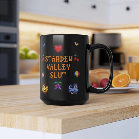 A black mug featuring pixel art graphics and the text Stardew Valley Slut sits on a wooden kitchen counter.