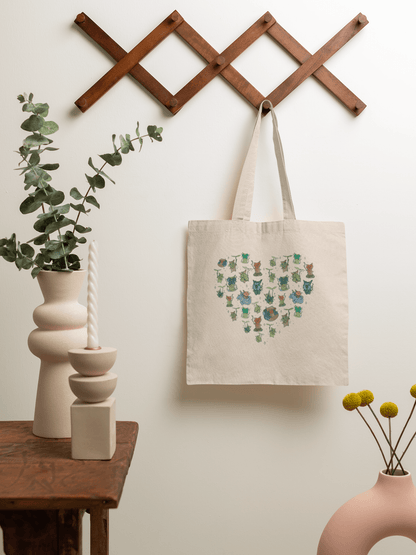 Legend of Zelda tote bag with a heart design of koroks hanging on a wooden rack against a white wall.
