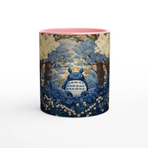 A ceramic mug depicts Totoro from Studio Ghibli sitting within a blue and pink chinoiserie-style cherry blossom forest scene.