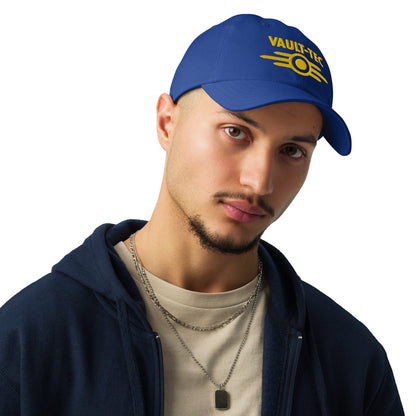 A person wears a blue Vault-Tec baseball cap with yellow embroidered lettering referencing the Fallout video game series.